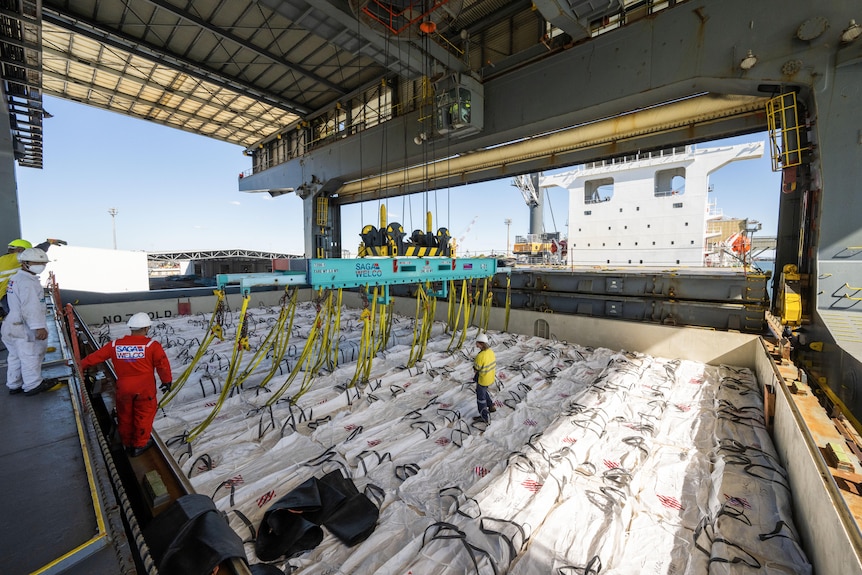 cotton in bags being loaded onto a ship.