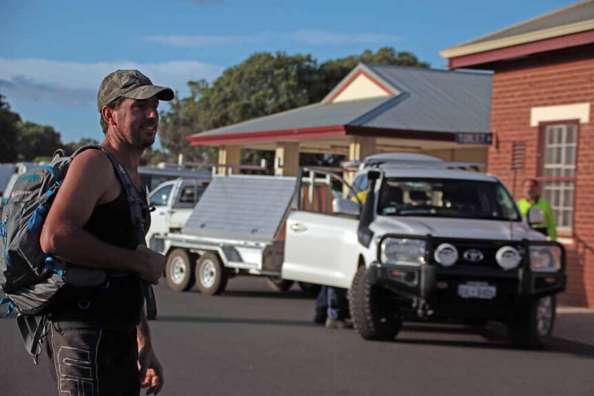 Man with backpack and cars in the background with trailers