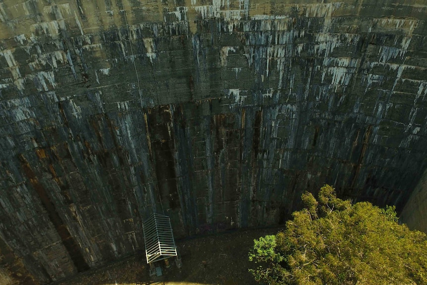 The steep wall of Tasmania's Ridgeway Dam, it is old and discoloured