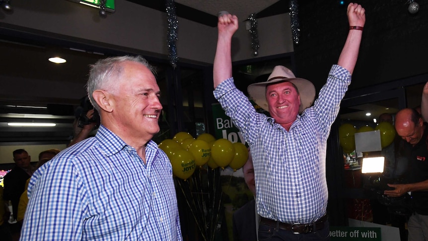 Barnaby Joyce with his arms in the air in excitement, Malcolm Turnbull stands beside him.