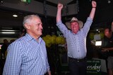 Barnaby Joyce with his arms in the air in excitement, Malcolm Turnbull stands beside him.