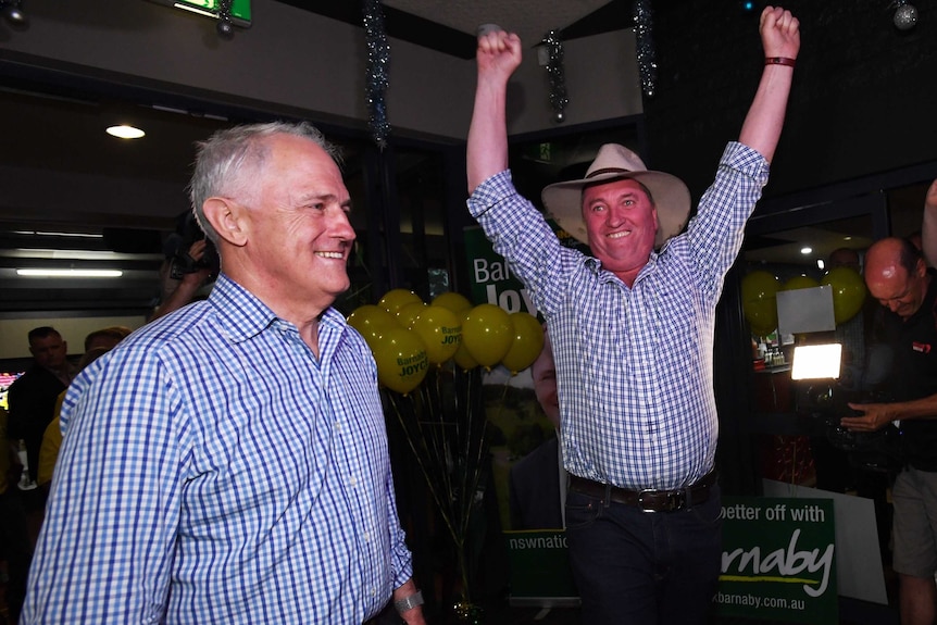 Barnaby Joyce with his arms in the air in excitement, Malcolm Turnbull stands beside him.