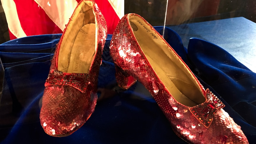 A pair of sparkly red slippers worn by actress Judy Garland in the "Wizard of Oz" sitting on a display.