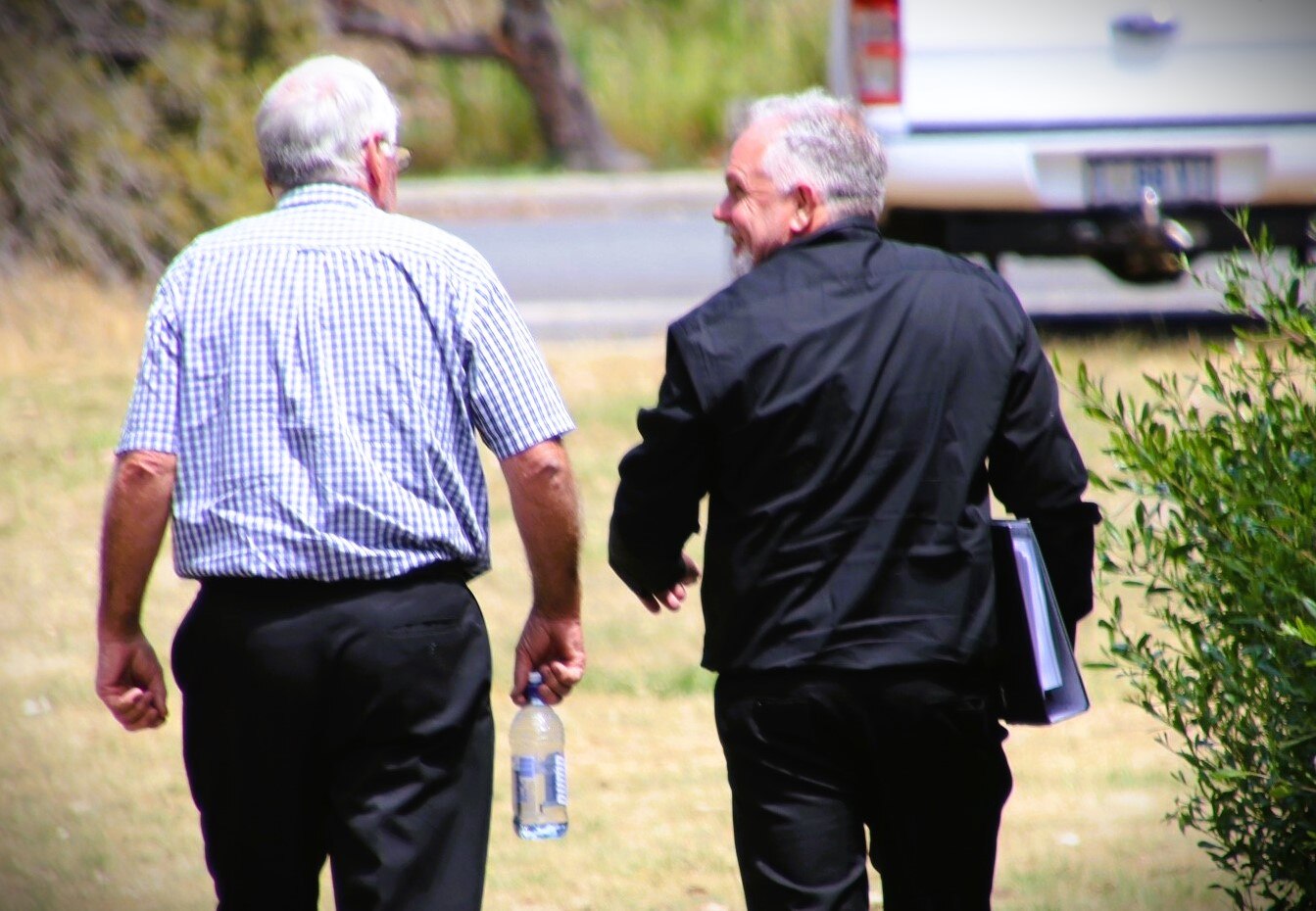 Two men walking, as seen from behind.