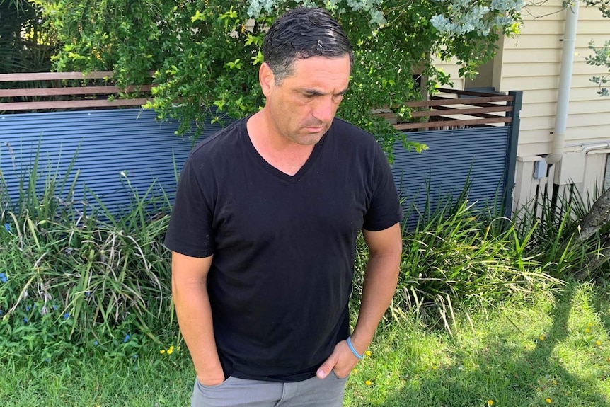 A man staring at the ground as he contemplates the violent killings of a Brisbane family