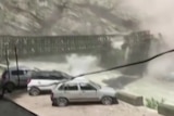 A small bridge collapsing after being hit by a rock boulder.  