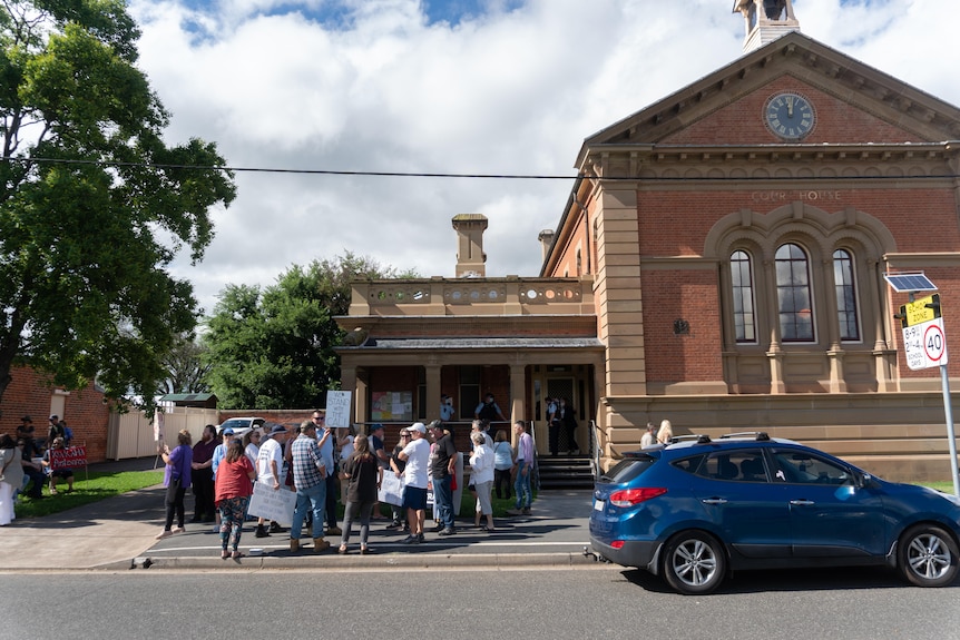 A group of protesters stand outside a courthouse.