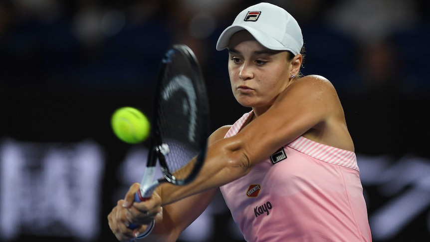 A female tennis player hits a shot with two hands