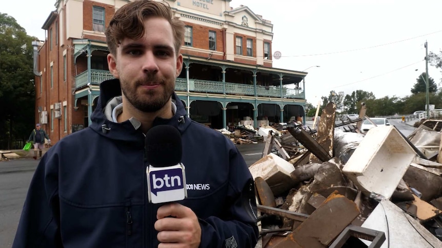 Cale standing on a street in Lismore, surrounded by flood debris.