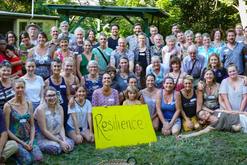 A large group of people posing for a photograph holding a sign with the word 'resilience'.