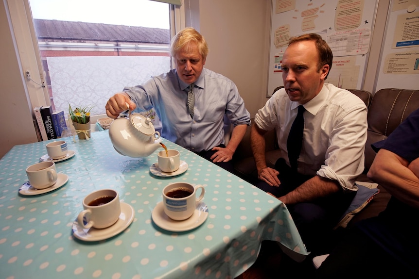 Boris Johnson pours Matt Hancock a cup of tea.