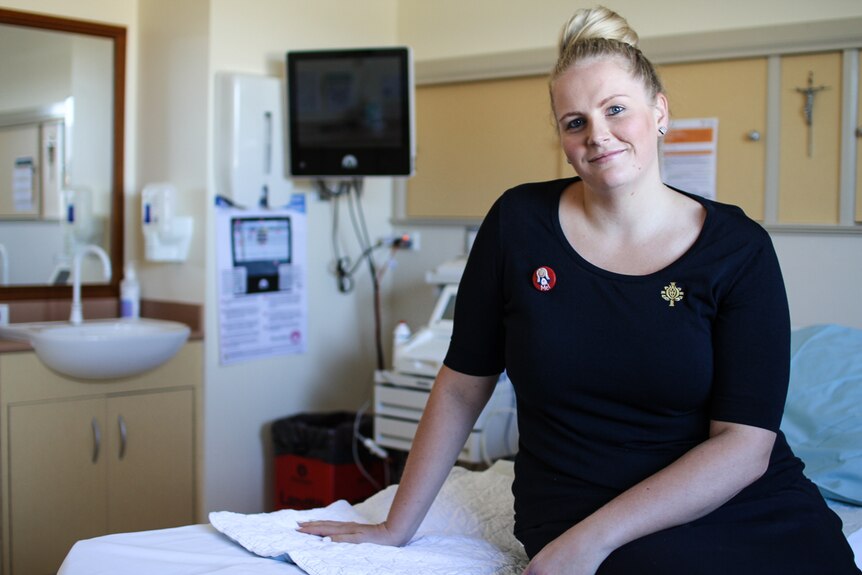Midwife Melissa Corbett from Bendigo's St John of God Hospital sitting on a hospital bed in a birthing suite.