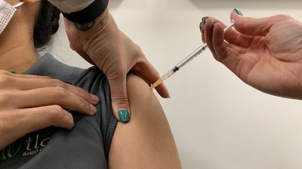 Vaccination being given in arm with needle.