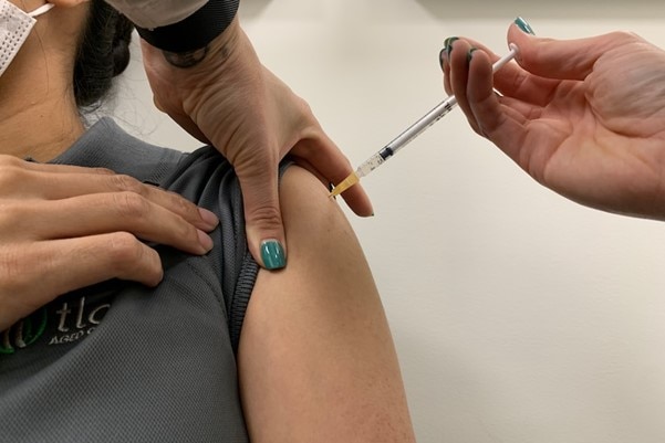 Vaccination being given in arm with needle.