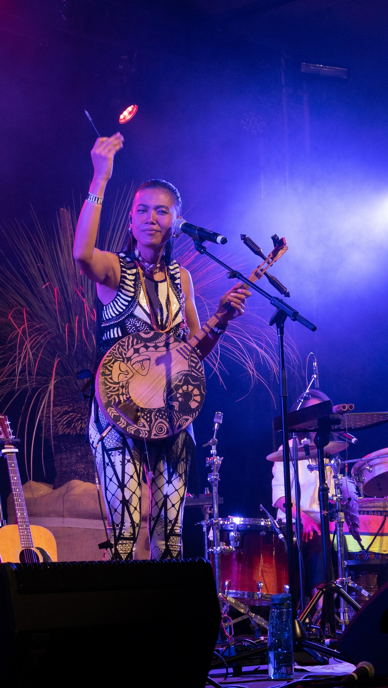 Musician carrying a yeuqin instrument raises her arm in the air performing on stage