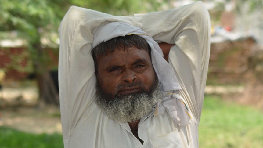 A closeup of a Muslim man in India as he stretches his arms.