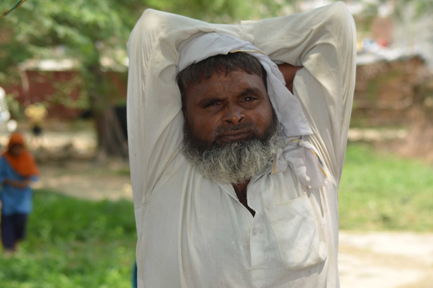 A closeup of a Muslim man in India as he stretches his arms.