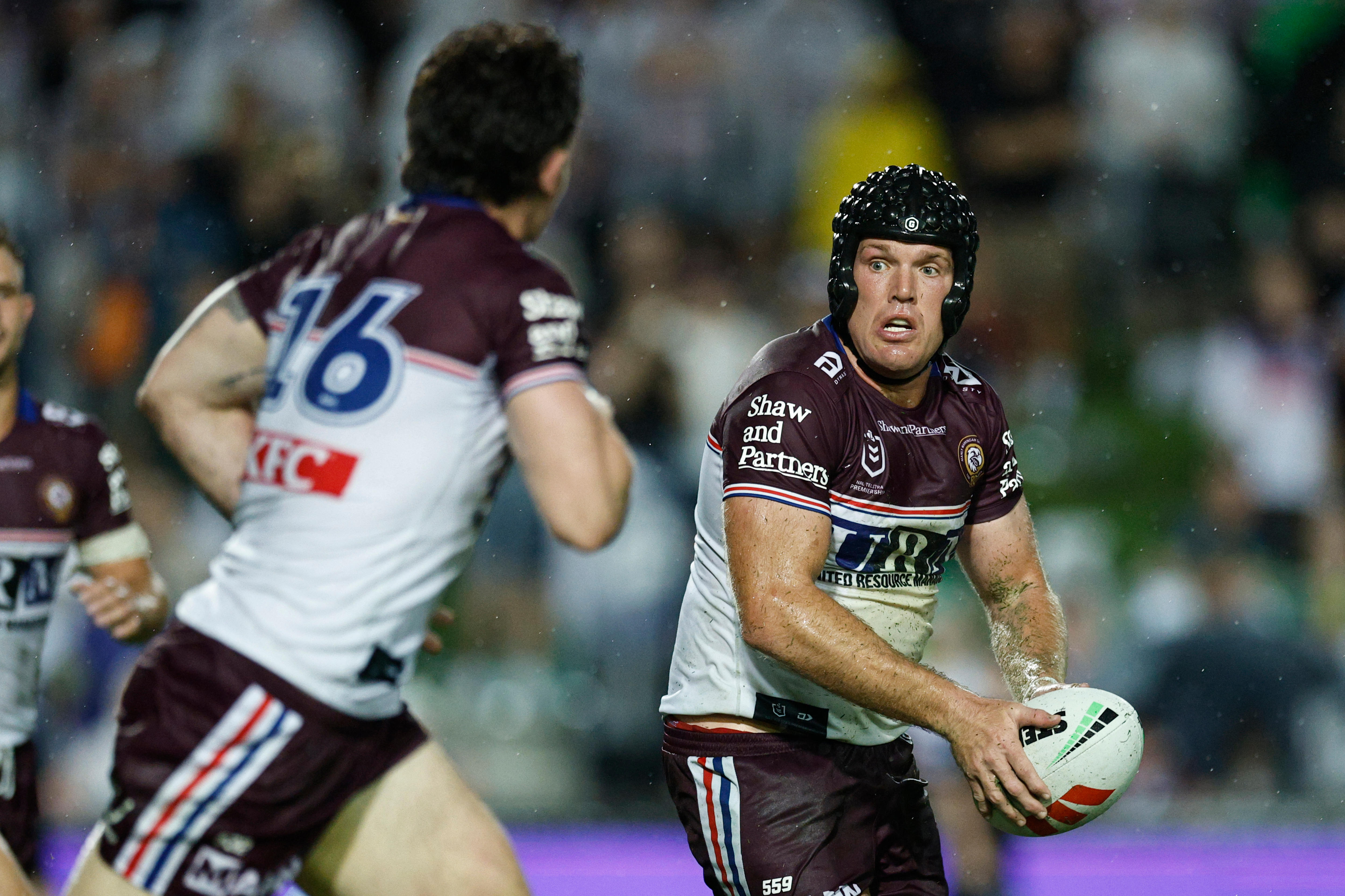 Um jogador de rugby usando um capacete preto acolchoado parece passar a bola.