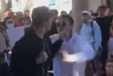 A still of a video showing a man in a black jacket and a man in a white jacket throwing punches.