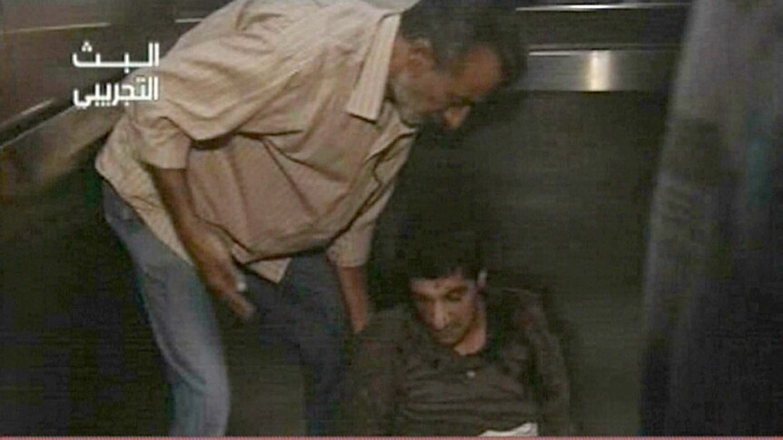 A Syrian man helps a wounded colleague