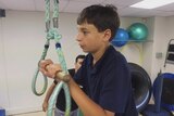 Goran holds on to a handle suspended by ropes in an exercise room.