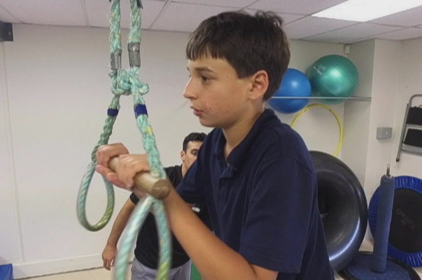 Goran holds on to a handle suspended by ropes in an exercise room.