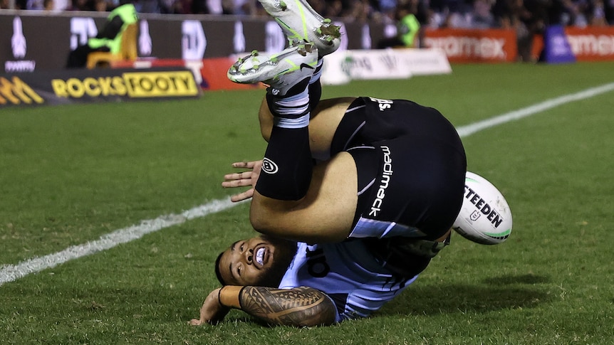 Cronulla Sharks NRL player Siosifa Talakai rolls upside down after scoring a try against the Manly Sea Eagles.