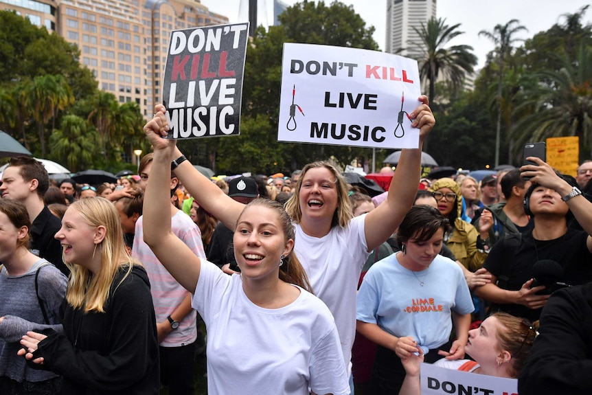 Two women hold signs that read: Don't Kill Live Music.