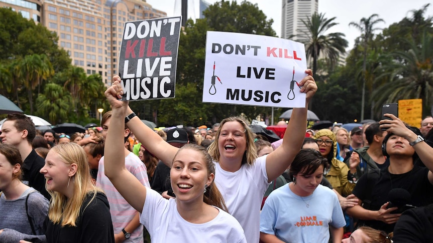 Two women hold signs that read: Don't Kill Live Music.