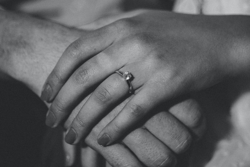 A black and white photo of a hand with a ring on it
