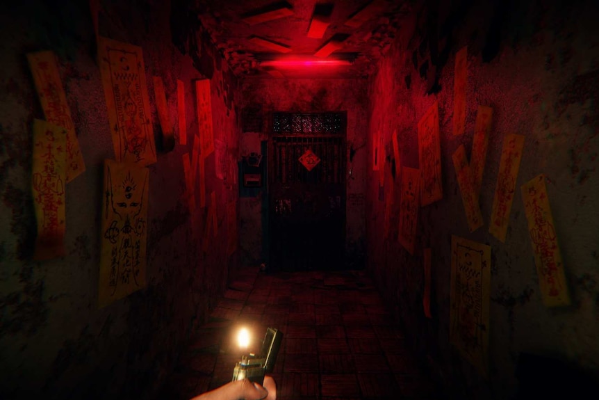 A dark corridor lit with a red light and covered in talismans.