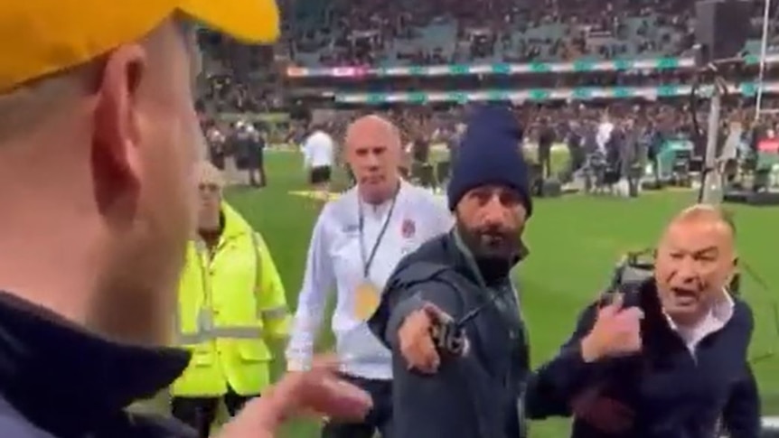 England rugby coach Eddie Jones shouts from the SCG field at a fan wearing a gold cap.