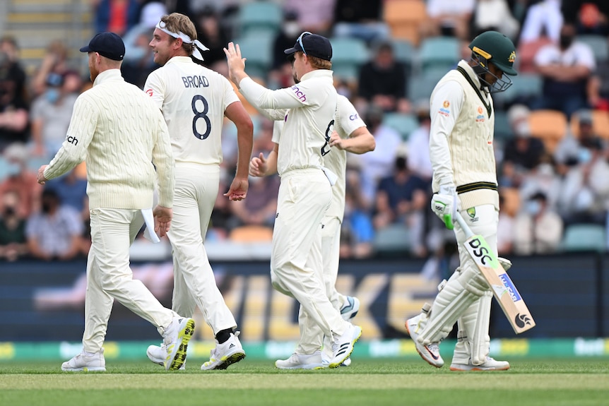 Australia batter Usman Khawaja (right) walks off as England players congratulate Stuart Broad.