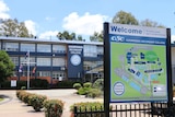 An image showing the entrance to Coorparoo Secondary College, with a school sign and map in front of gardens and navy building
