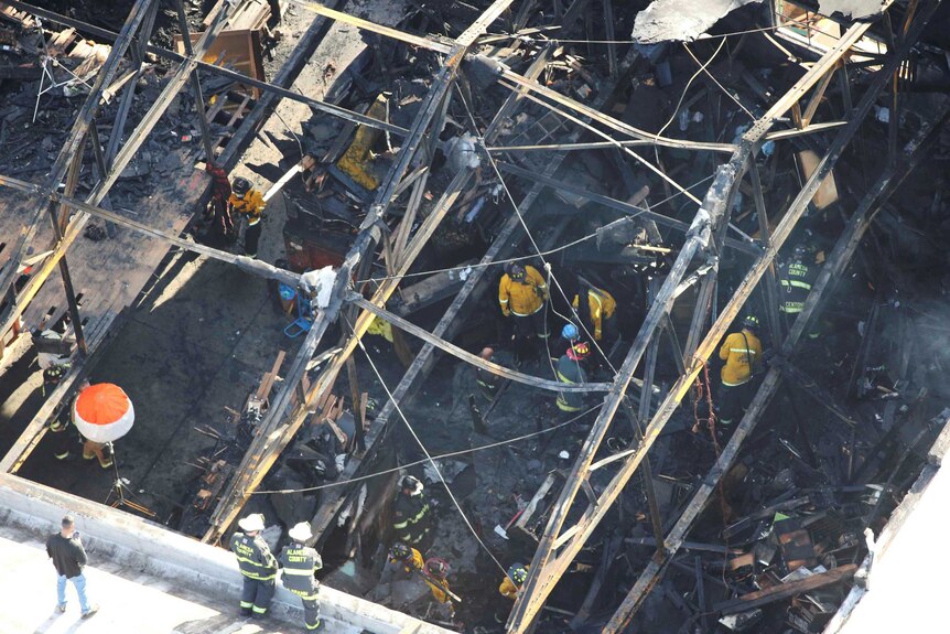 Recovery teams examine ruins of a warehouse that caught fire in California.
