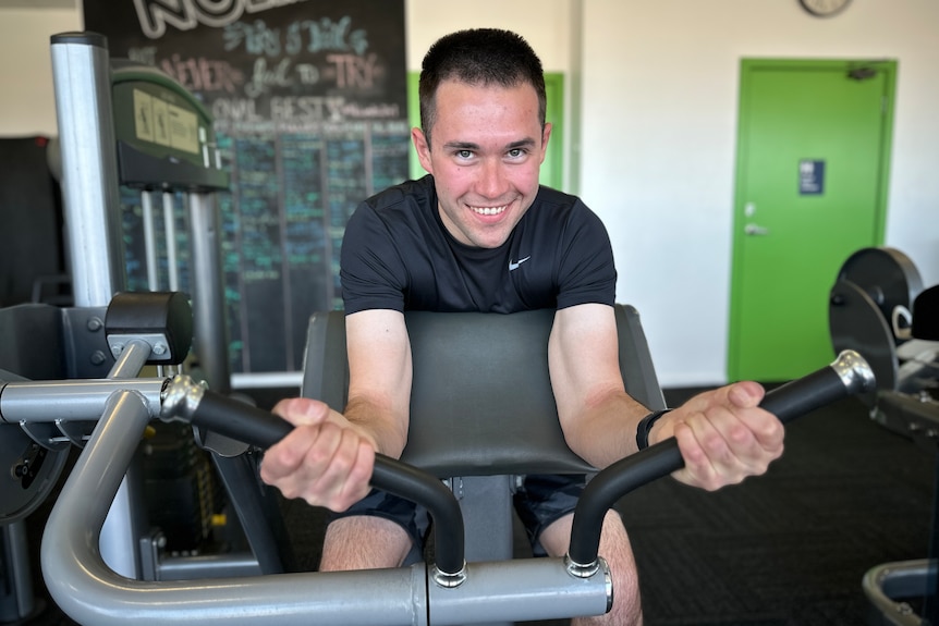 A man in a black t-shirt ride an exercise bicycle