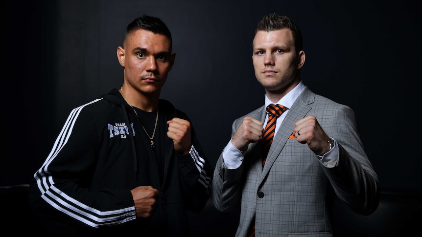Jeff Horn, right, wearing a grey suit and yellow and black tie, and Tim Tszyu, wearing a black tracksuit, pose with their fists