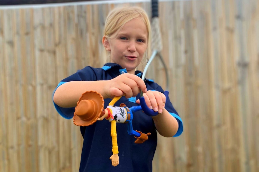 Sylvana in the backyard, holding a Sheriff Woody doll.