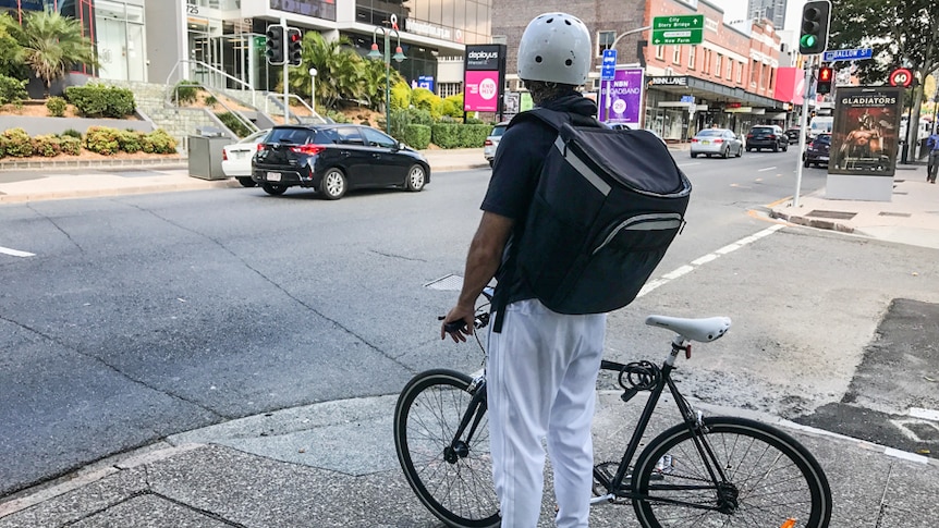 Food delivery cyclist waiting to cross the road.