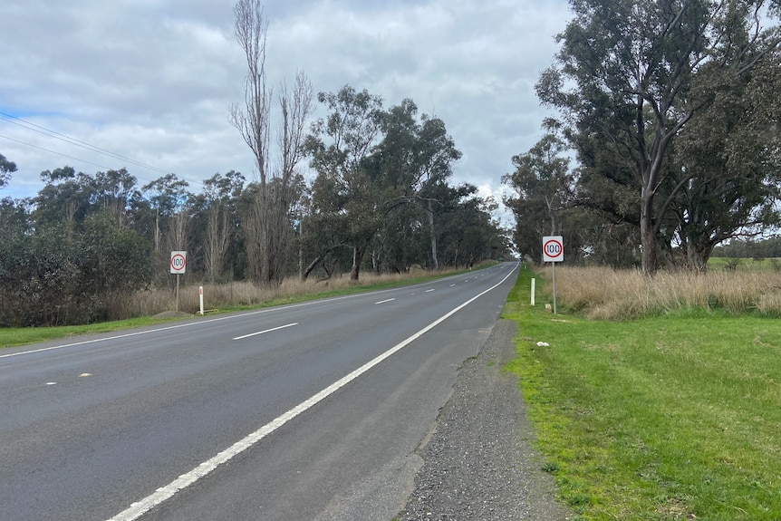 A stretch of road, surrounded by trees and grass, with signposted speed limits.