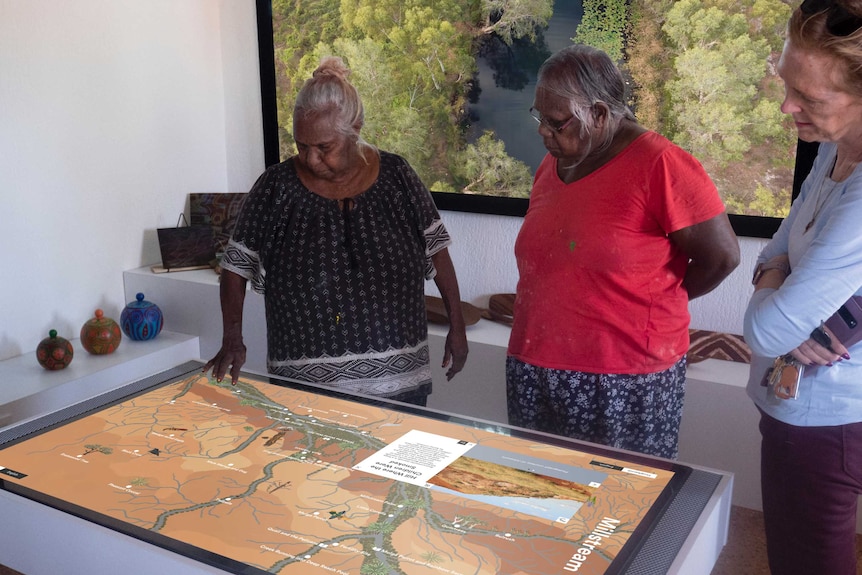 Three women look at a map on an interactive table.