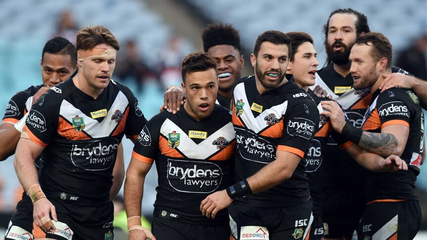Tigers players celebrate a try against the Dragons
