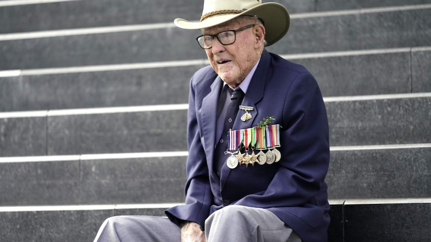 elderly man in hat sitting on stairs with hands clasped