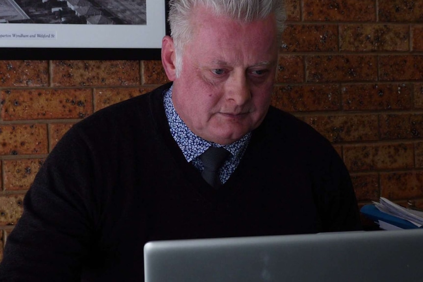 A man with grey hair looking at a computer screen.