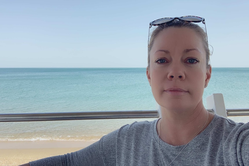 Trinity Rafferty with her sunglasses on her head and the ocean in the background.