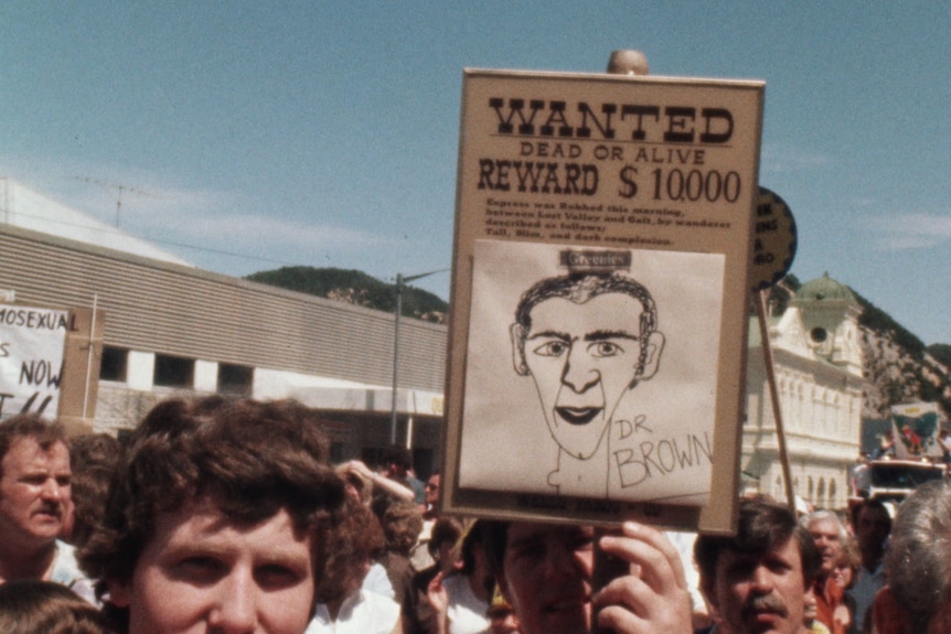 A crowd of people around a sign that says: "Wanted dead or alive" and a drawing of Bob Brown.
