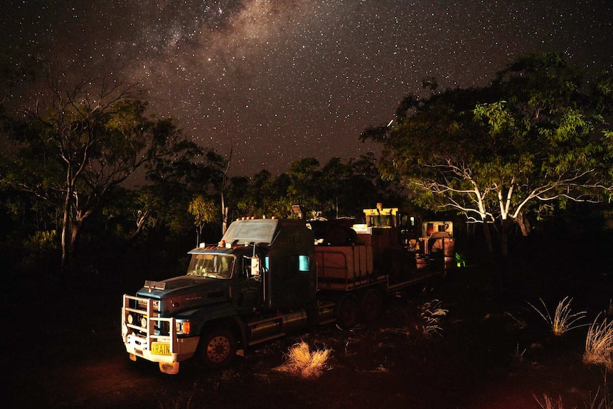 A truck in the bush with stars in sky