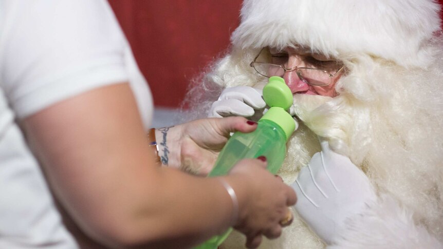 Santa John is helped to a drink of water through a straw.