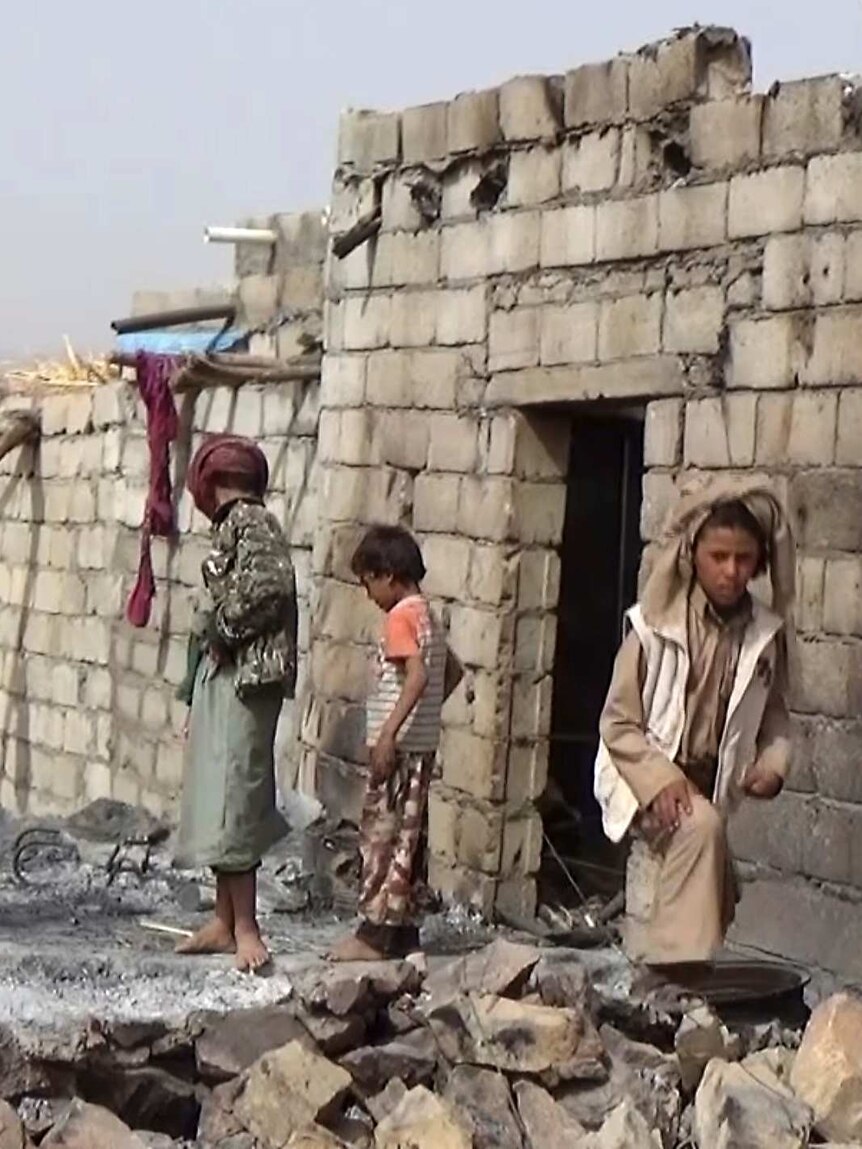 Three children and a man assess the damage of a house in Yemen after a US raid