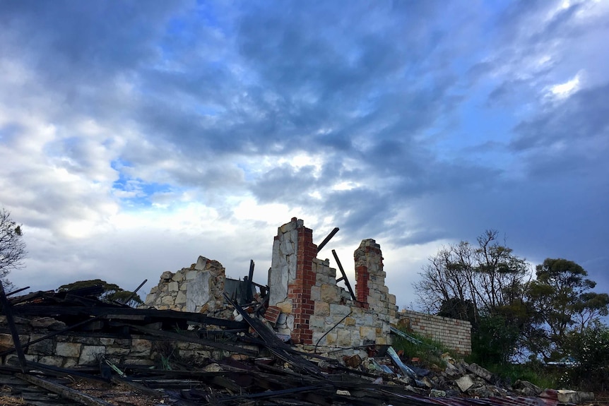 A house ruins sit beneath a stormy sky